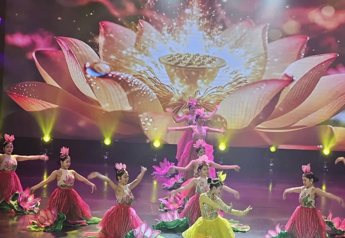 Ao Dai Show, dancers in a lotus scene under a giant lotus on the screen behind