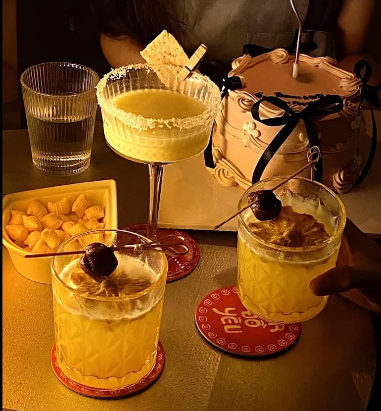 Cocktails beside a little cake at Bar Đồ Yêu