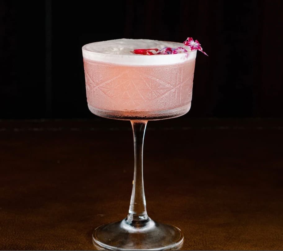 C Bar, a pink cocktail in a coupe glass with a flower on the rim