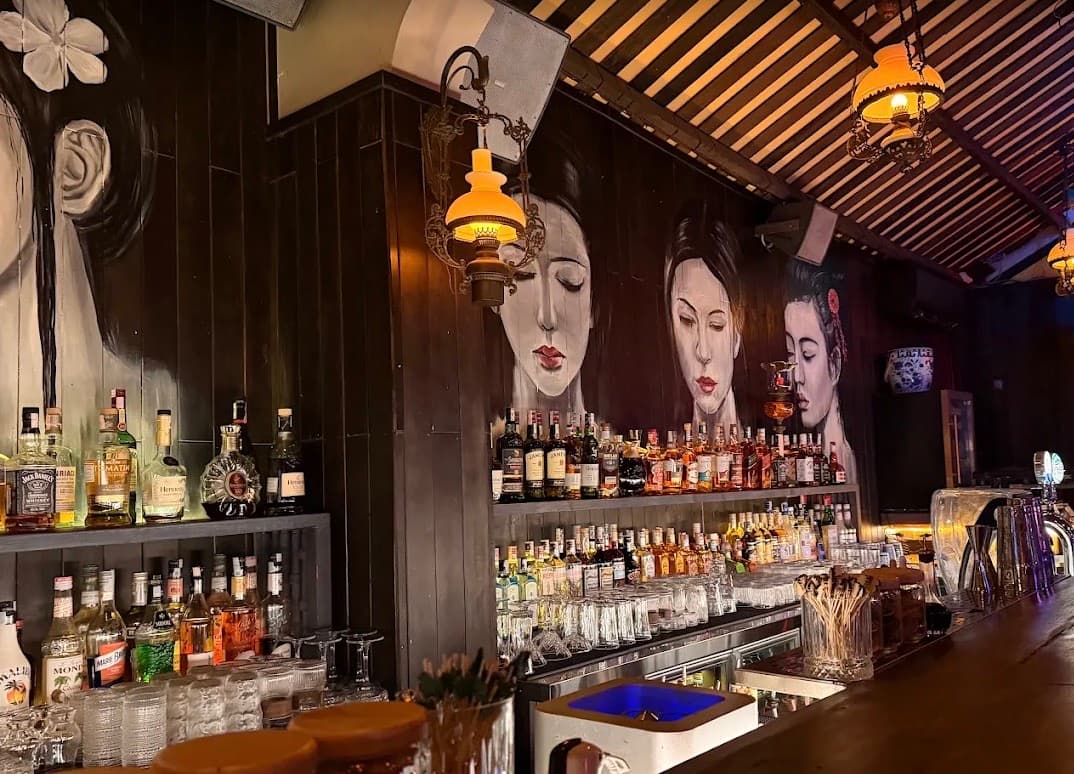 C Bar, the bar counter with bottles on the shelves and large painted faces on the wall behind