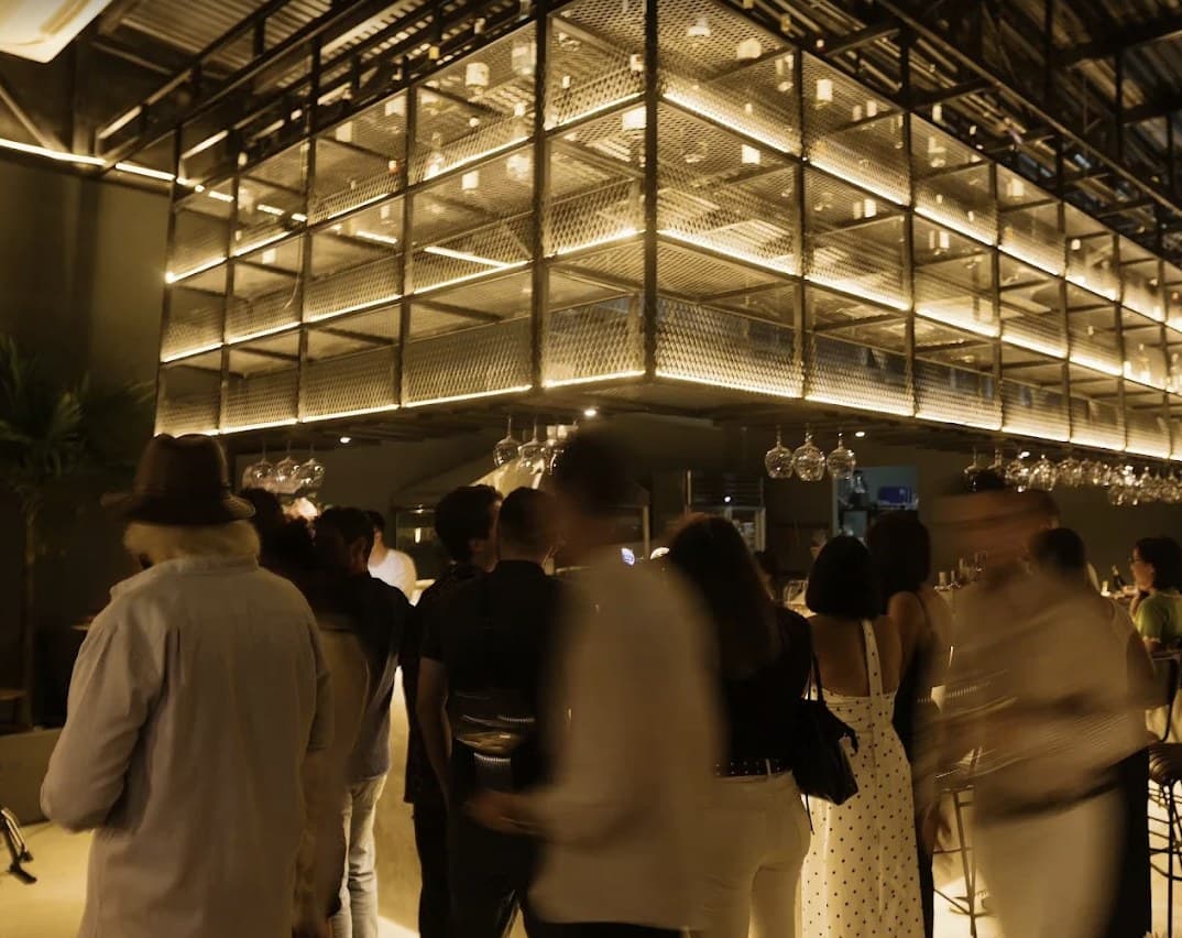 The room full of guests under the lit wine rack at Cáliz Wine Bar