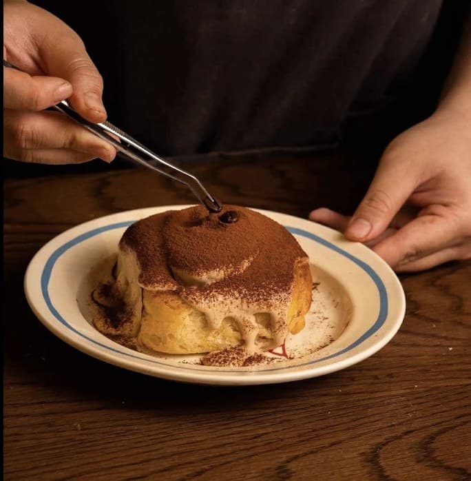 A cocoa dusted cinnamon roll being finished by hand at Chupchip