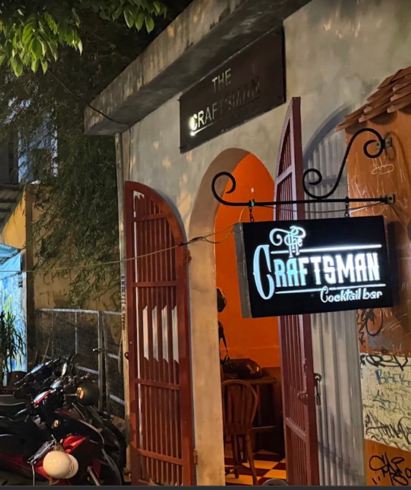 The Craftsman, the arched wooden door and lit sign on Phan Tu at night