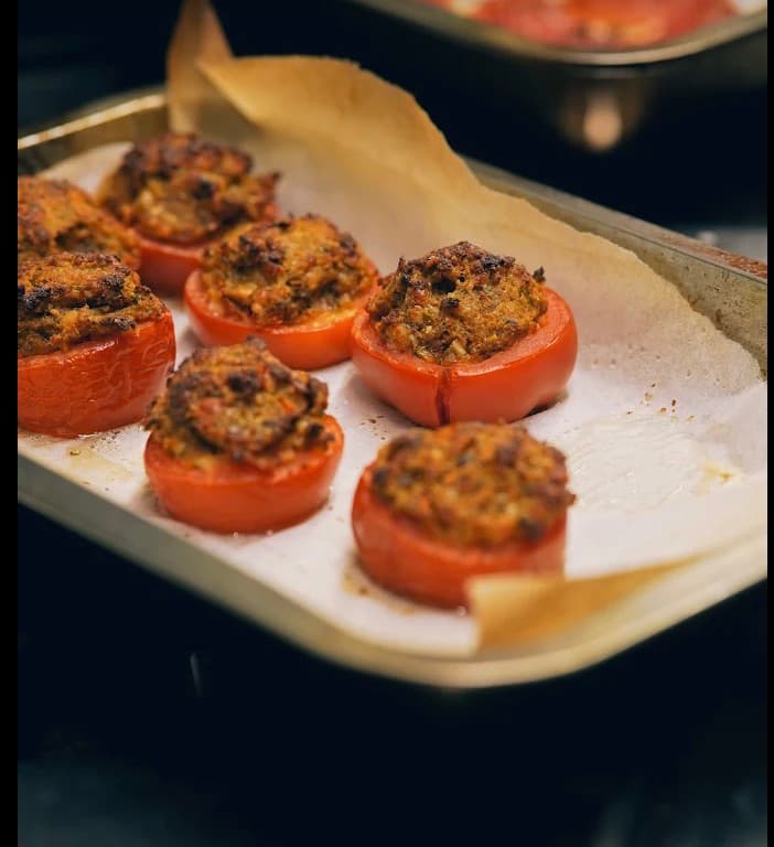 Cucina Luca, những nửa quả cà chua nướng nhồi nhân vàng trên khay lót giấy