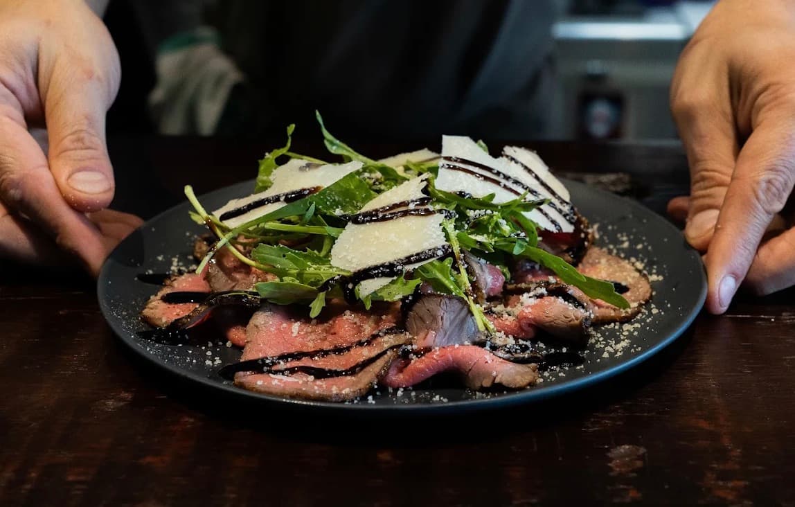 Cucina Luca, những lát bò mỏng phủ rau rocket, phô mai bào và sốt sẫm màu