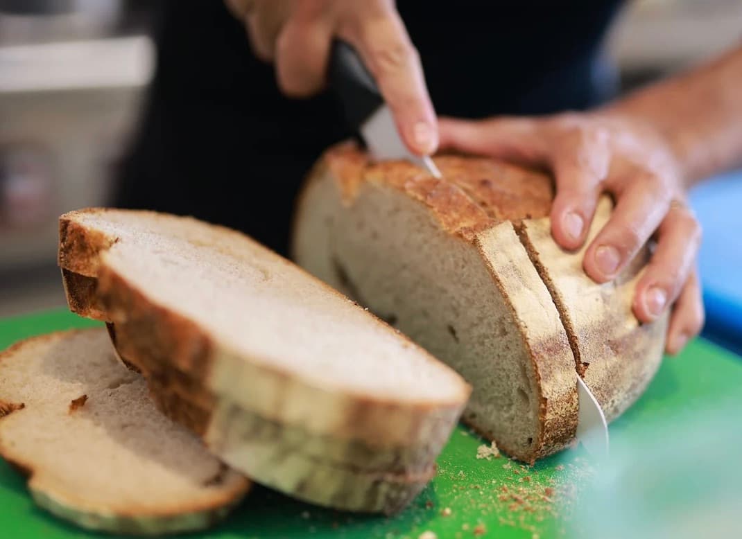 Cucina Luca, một ổ bánh mì tròn đang được cắt trên thớt xanh