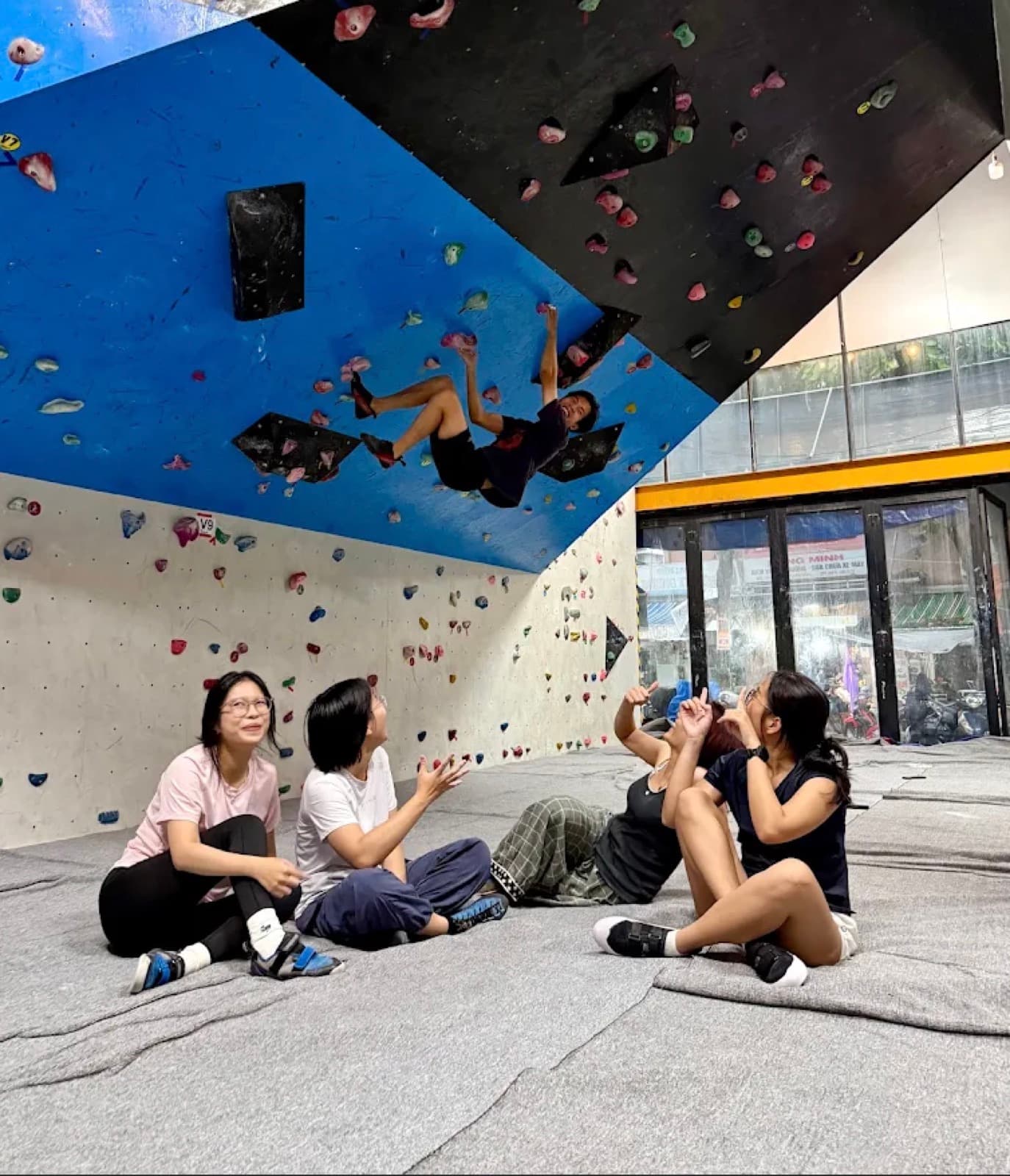 Climbers sitting on the foam floor at Danang Climbing Gym, watching someone on the wall