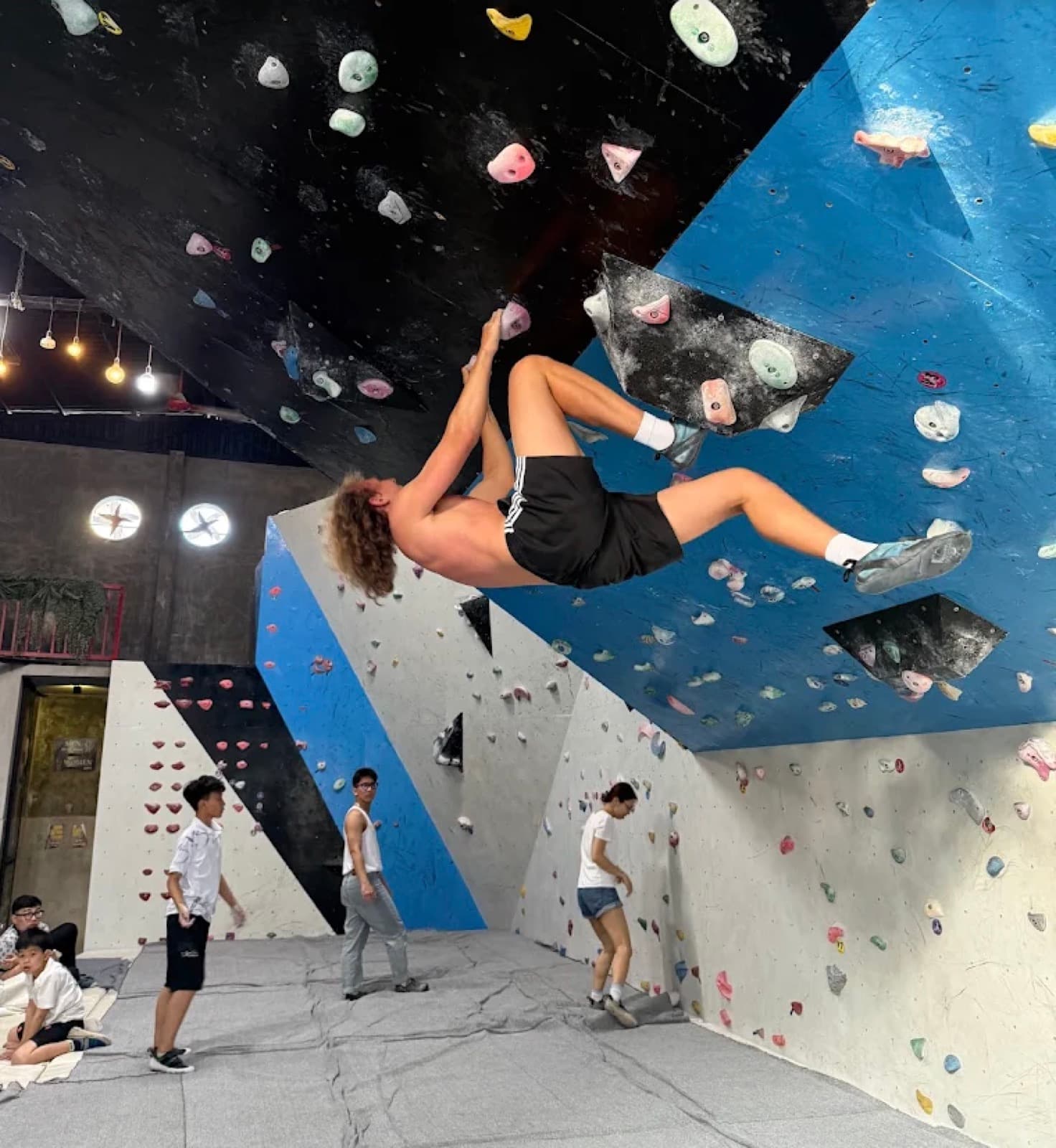 A climber hanging from the overhang at Danang Climbing Gym in Da Nang