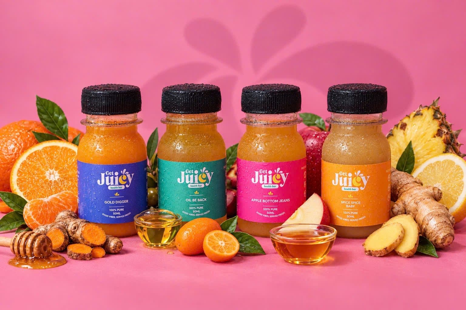 The four GetJuicy Health Bar shots, Gold Digger, Oil Be Back, Apple Bottom Jeans and Spice Spice Baby, with fruit and honey on pink