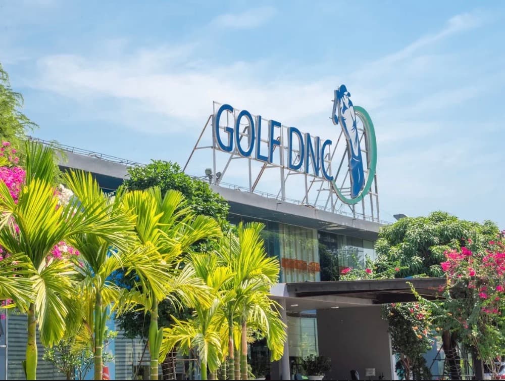 Golf DNC, the building with the Golf DNC sign on the roof, palm trees and flowers in front
