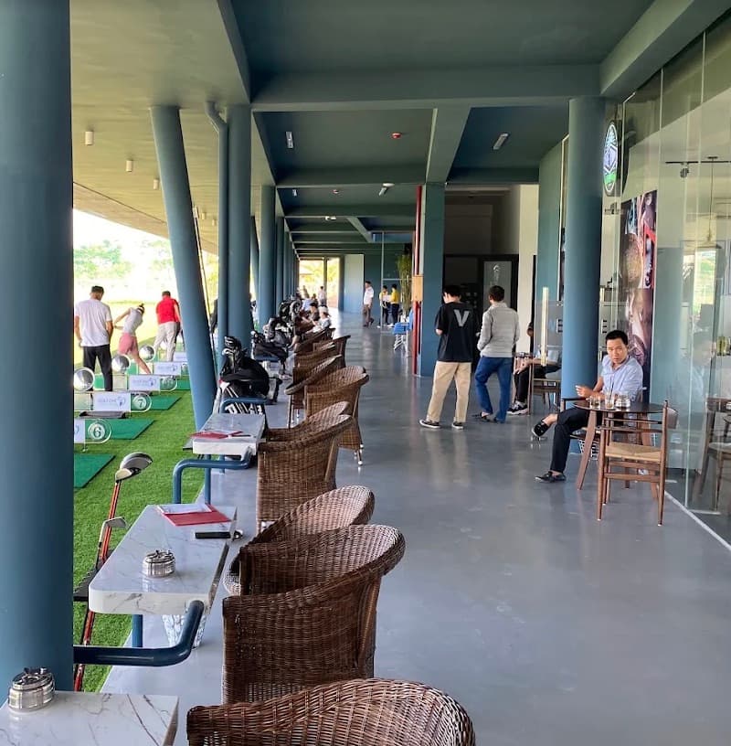 Golf DNC, the covered walkway behind the bays, with wicker chairs, tables and players at the mats