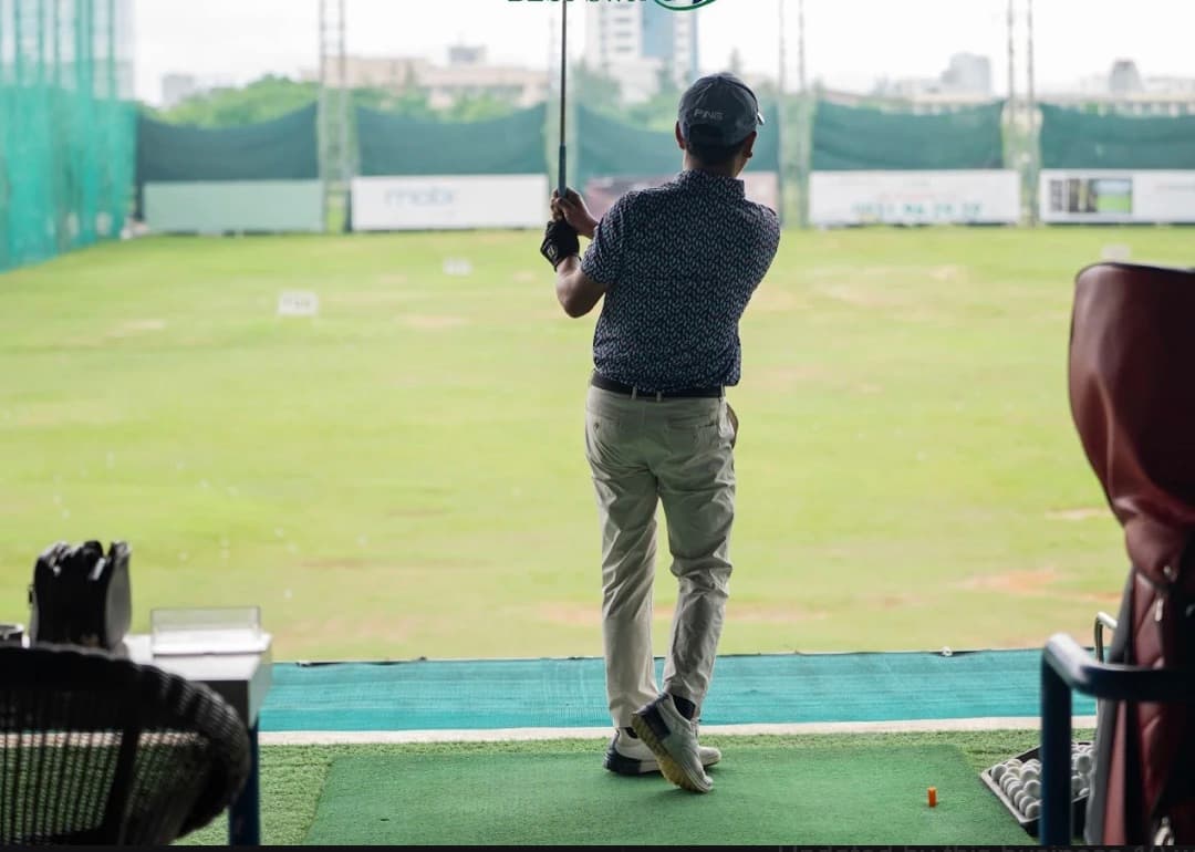 Golf DNC, a player mid swing at a bay, looking out over the field