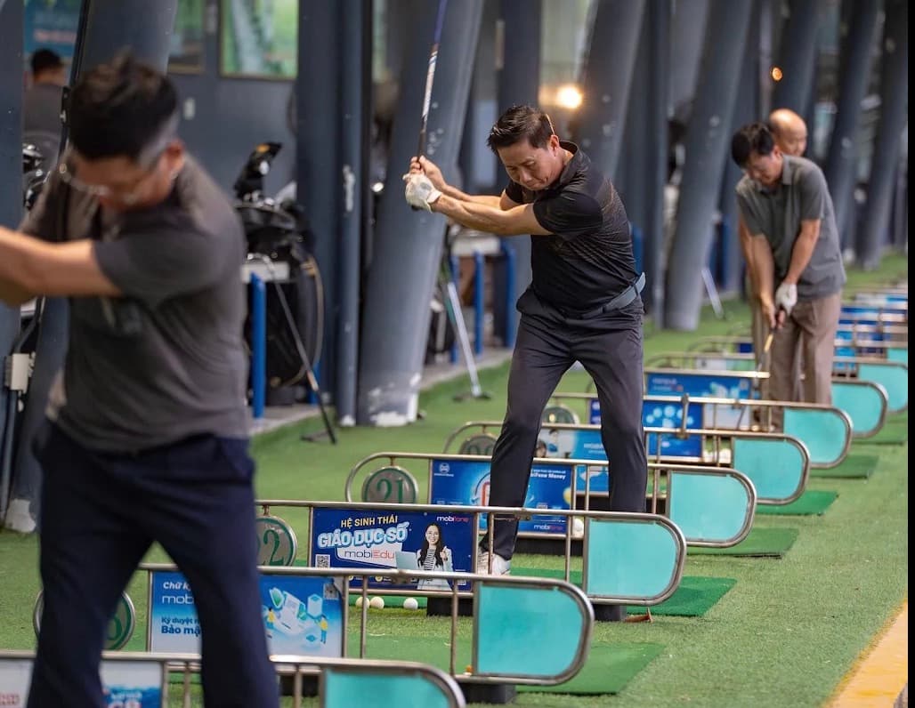 Golf DNC, a row of players swinging at numbered bays under the covered roof