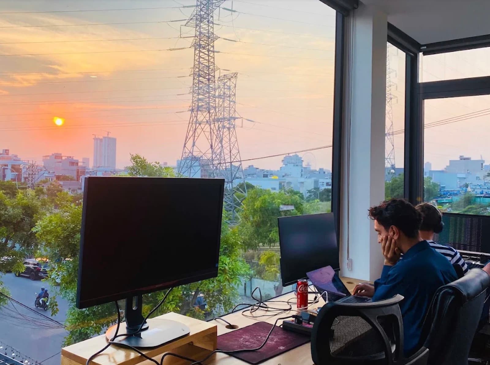 A desk by the window at Hana's Coworking as the sun sets over Da Nang