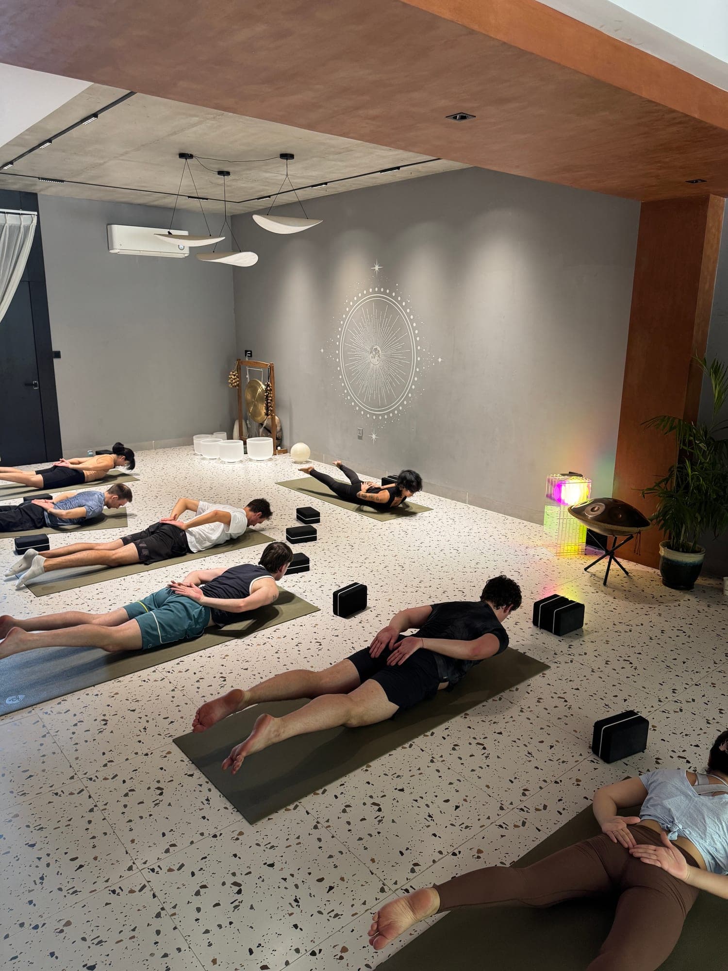 Toàn cảnh phòng tập ở Heart Studio by Chan nhìn từ trên cao, có lớp đang tập trên thảm, trên bức tường xám là hình trăng sao