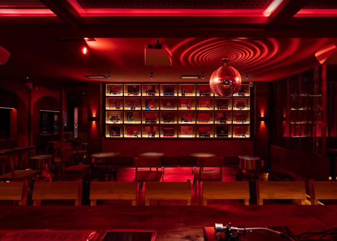 The wall of lit record sleeves at Midnight Condo, with a mirror ball and the bar in front