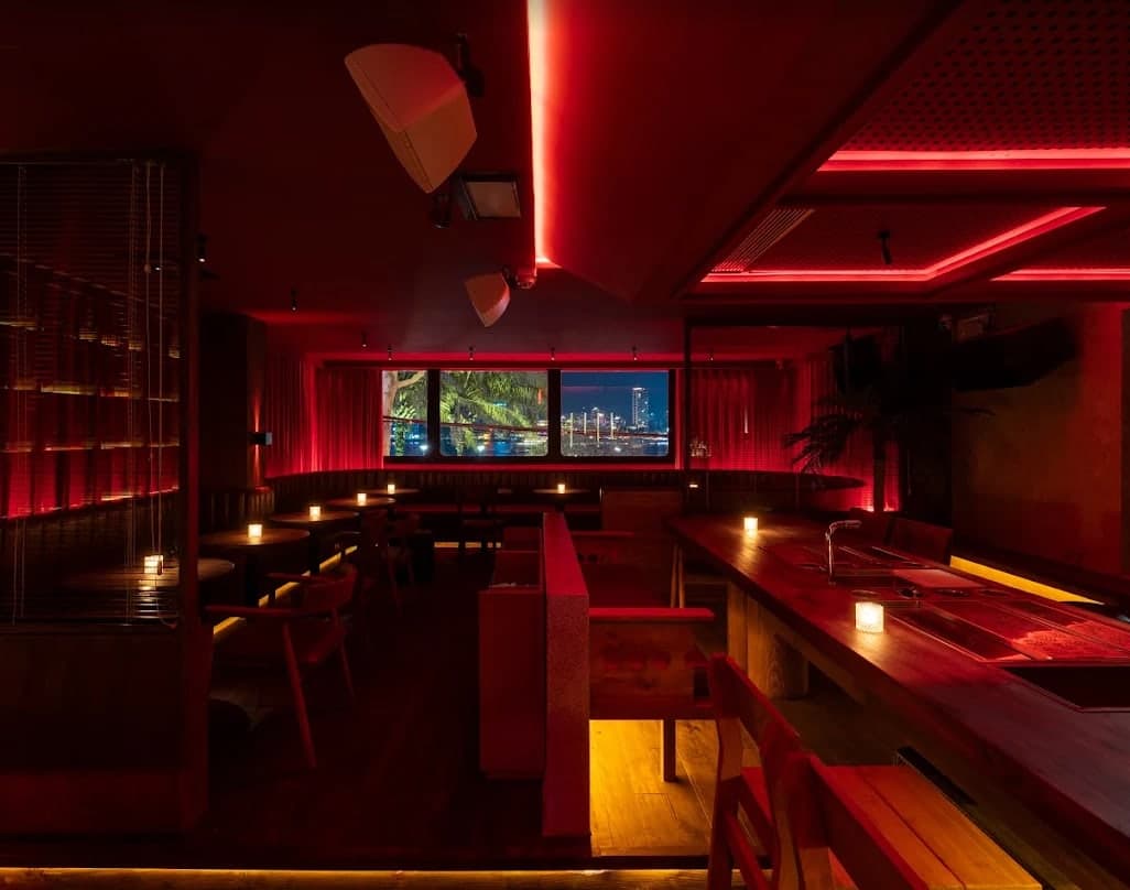 The room at Midnight Condo under red light, with a window onto the river and the bar