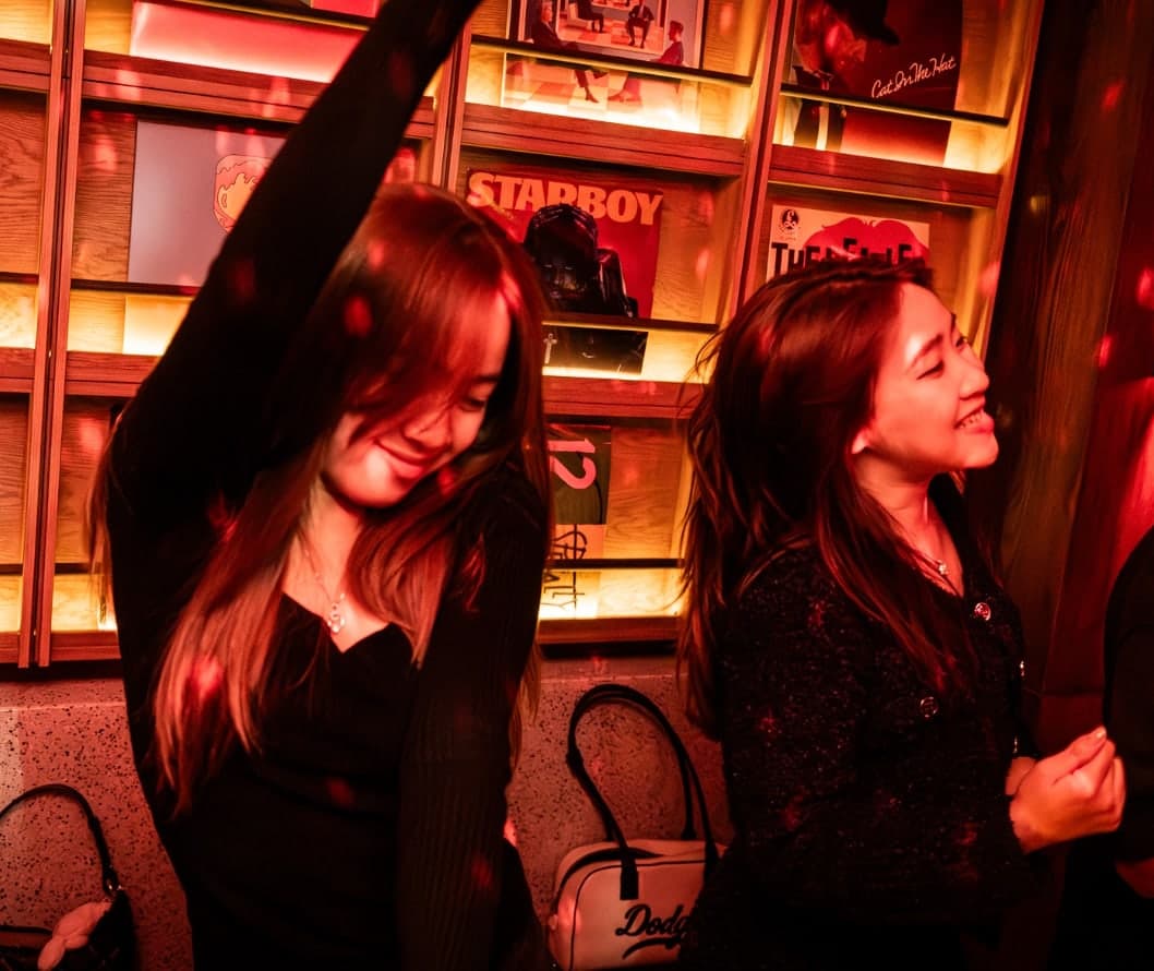 Two women dance in front of the record wall at Midnight Condo