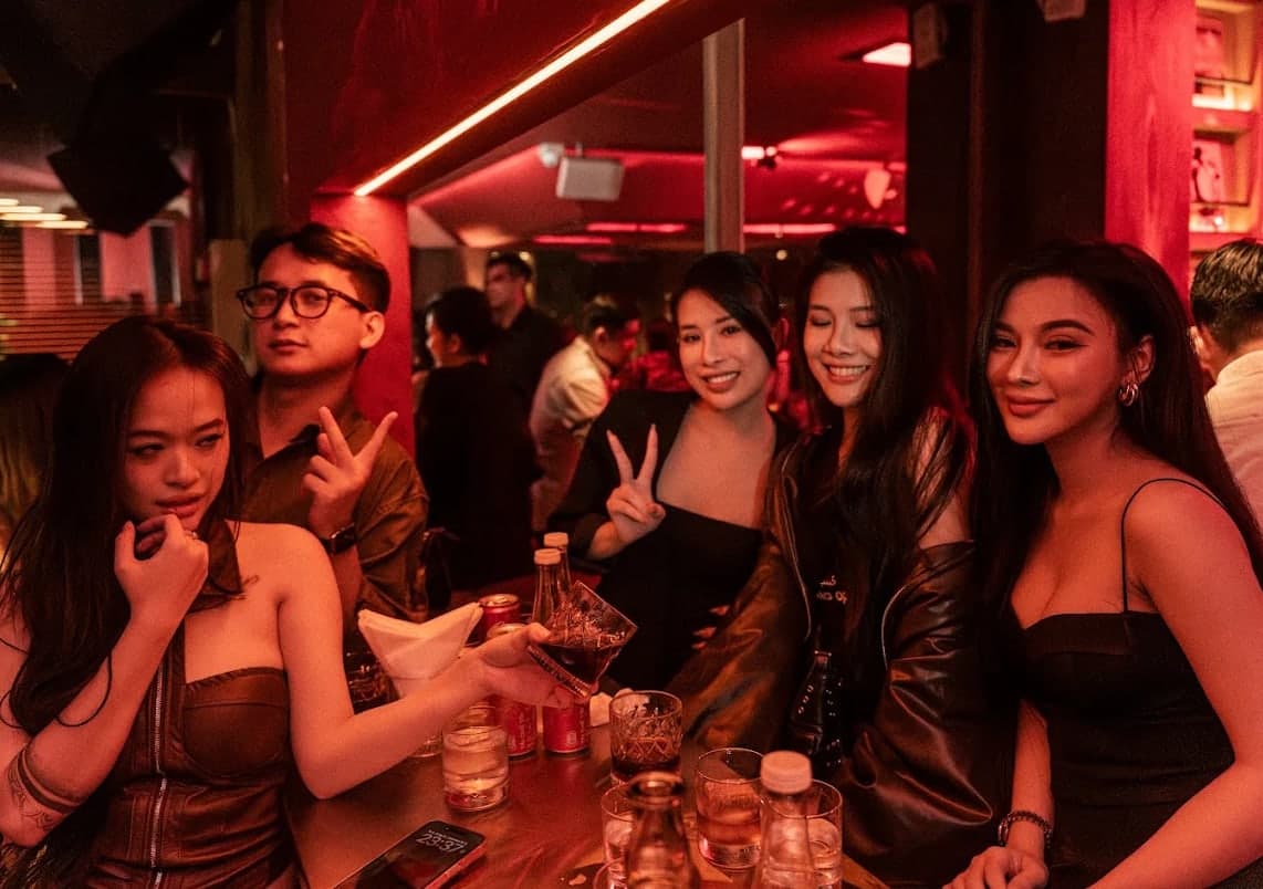 Five guests at the bar at Midnight Condo, two making a peace sign