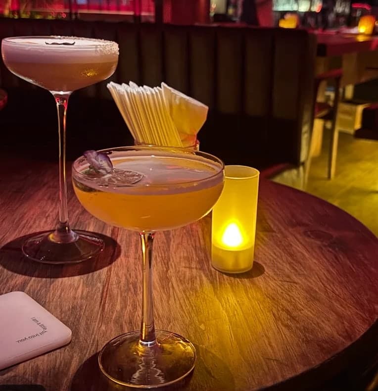 Two cocktails and a candle on a wooden table at Midnight Condo