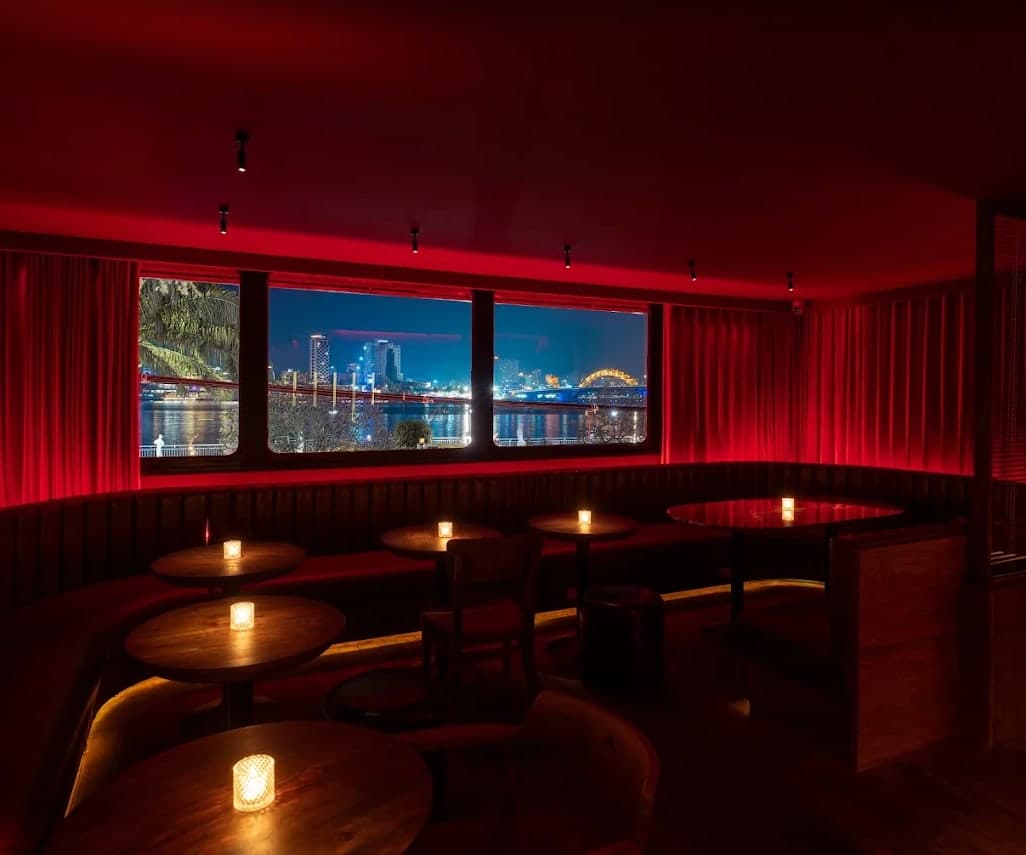 A booth by the window at Midnight Condo, with the river and the Dragon Bridge lit outside