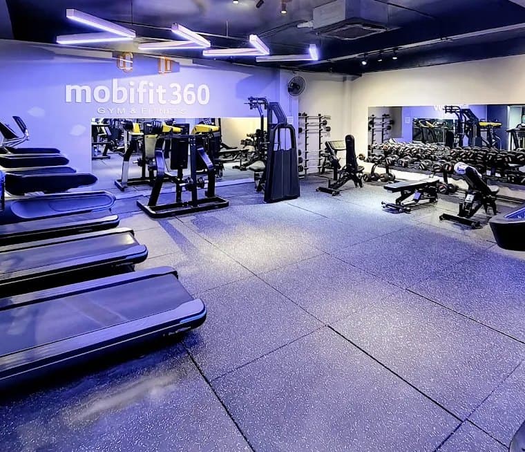 mobifit360 Gym & Fitness, sàn tập chính với tên phòng gym sáng đèn trên tường