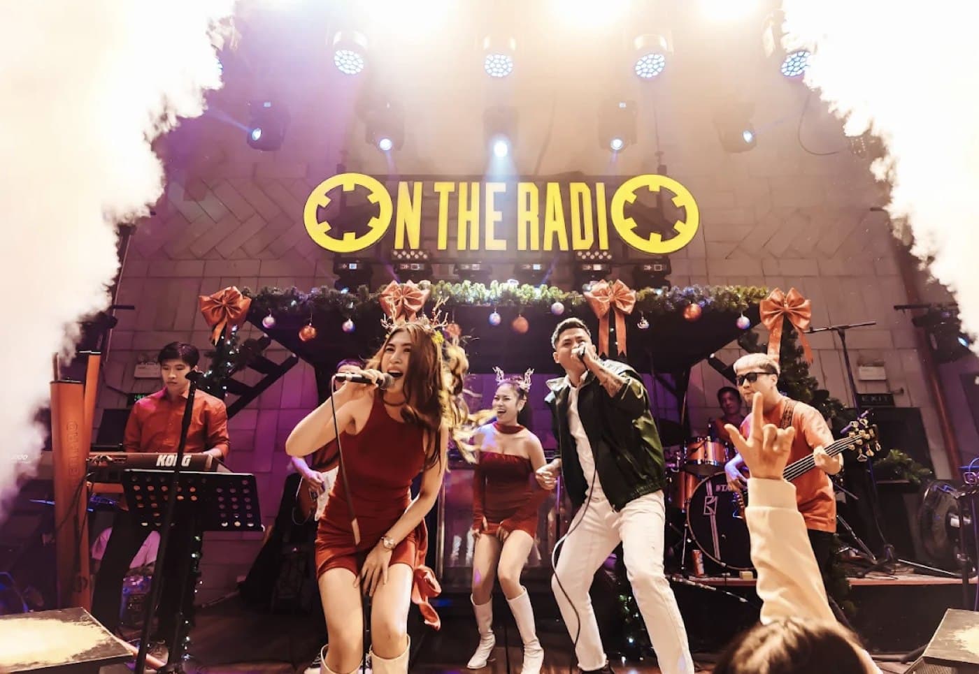 On The Radio singers on stage under the neon sign