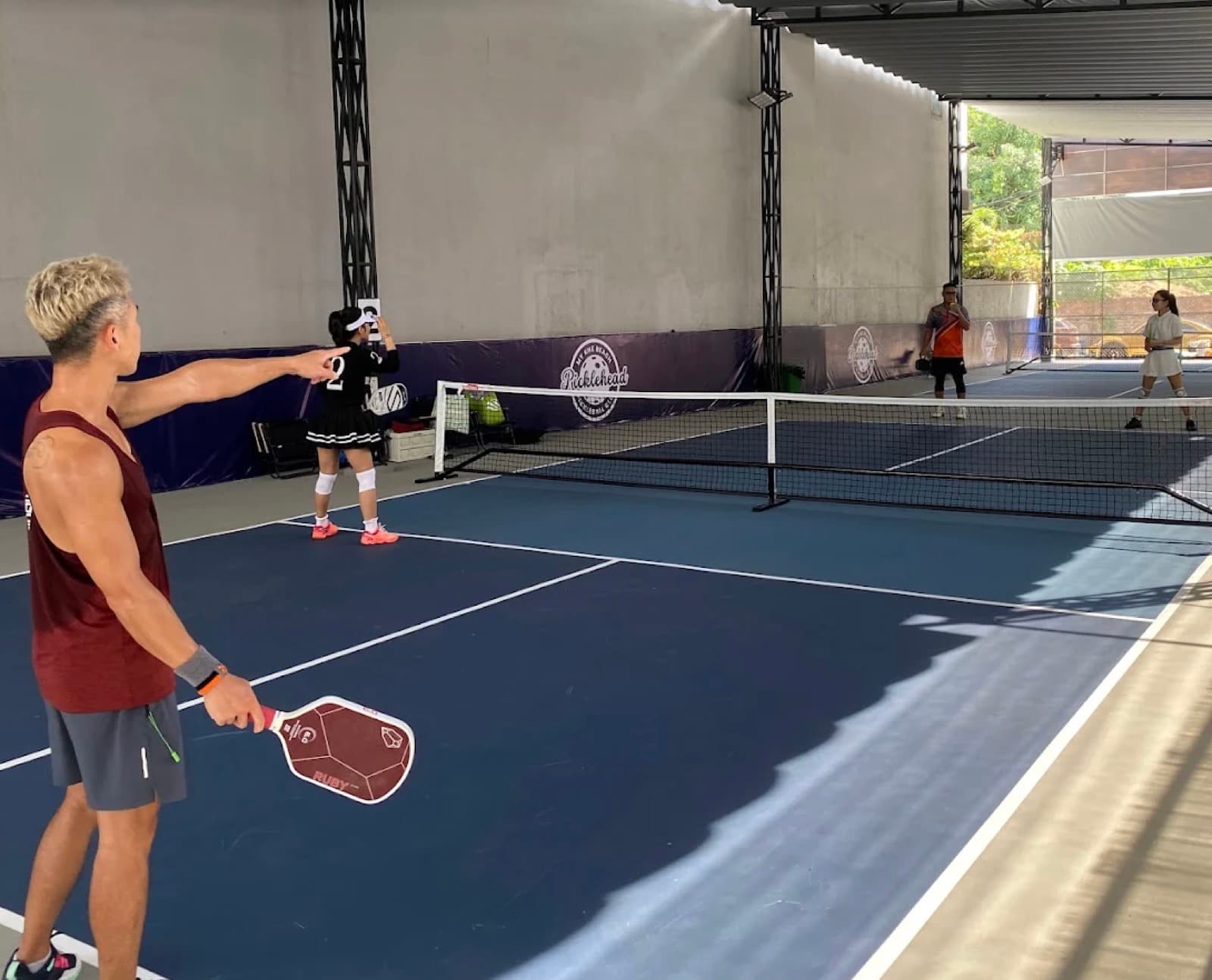 A doubles rally on the covered courts at Picklehead near My Khe Beach, Da Nang
