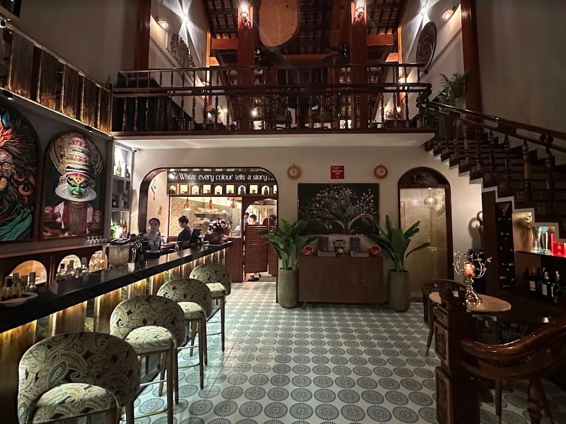 The bar and the double height dining room at RANG, with a staircase climbing past a mezzanine and the words where every colour tells a story painted above the kitchen pass