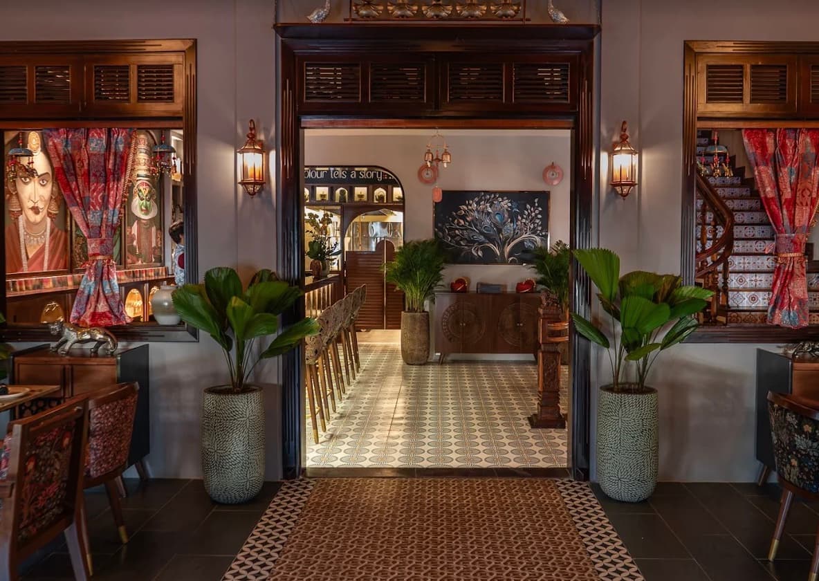 Looking through the carved wooden doorway of RANG in Da Nang, down a patterned tiled floor past tall palms to the back of the dining room