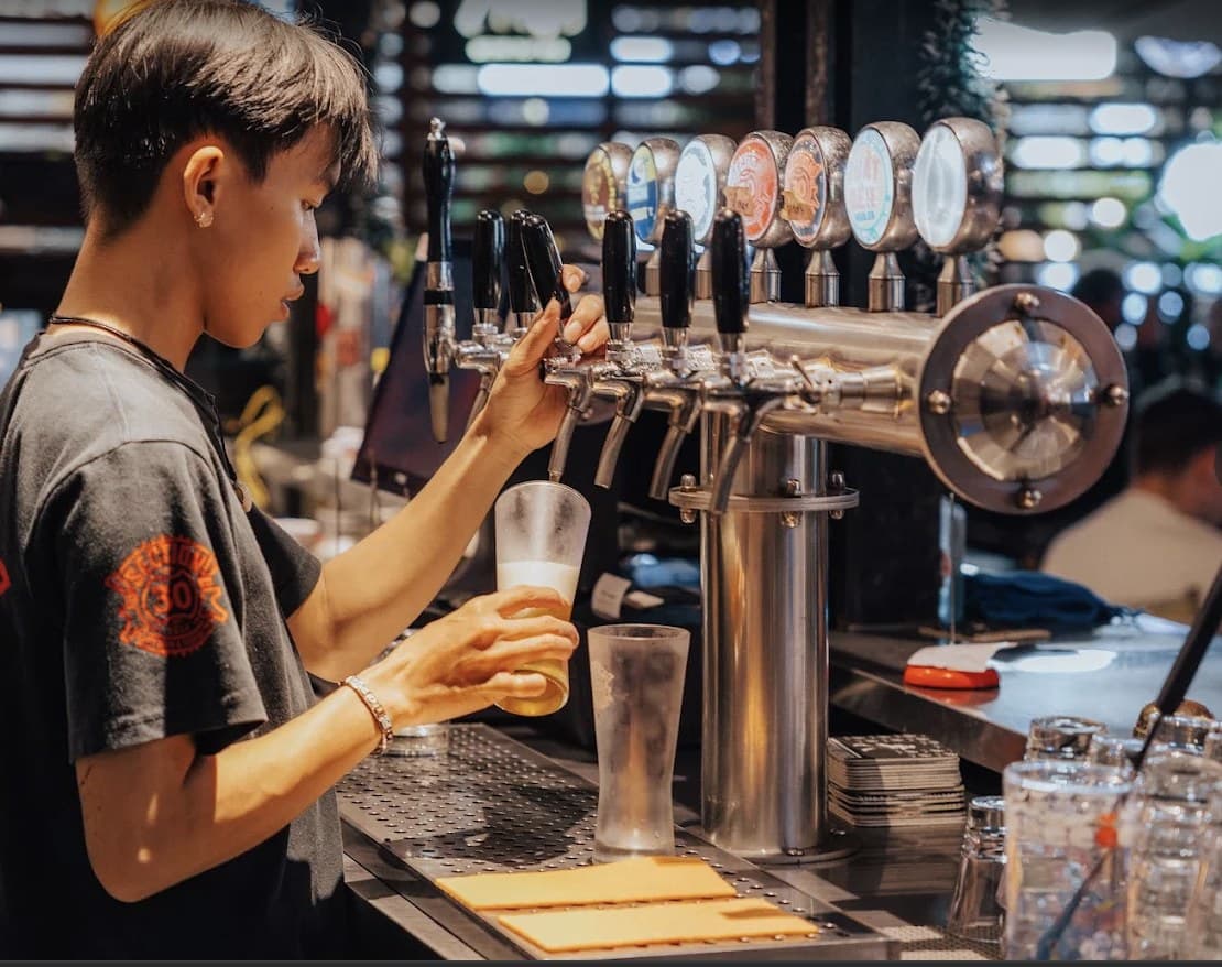 A row of craft beer taps being poured behind the bar at Section 30