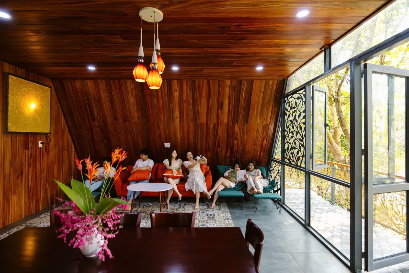 Suối Lương Hải Vân Park, a group of friends on red sofas in a wooden villa with tall glass windows