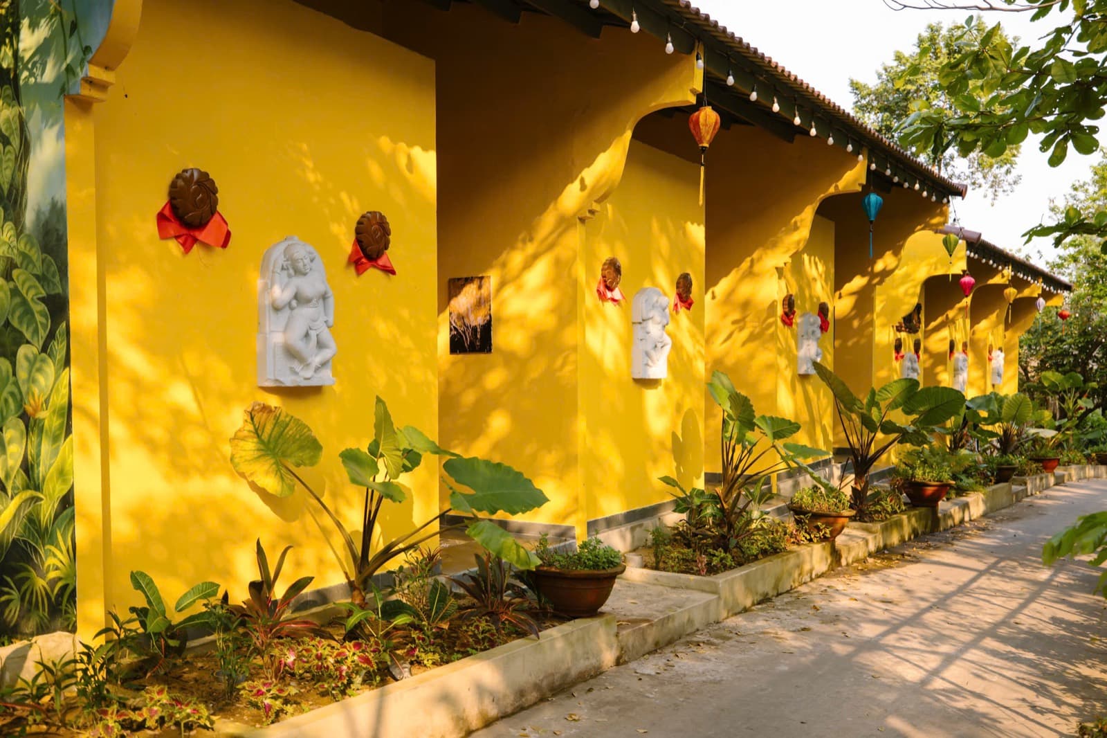 Suối Lương Hải Vân Park, a row of yellow walls with white carved reliefs, lanterns and plants