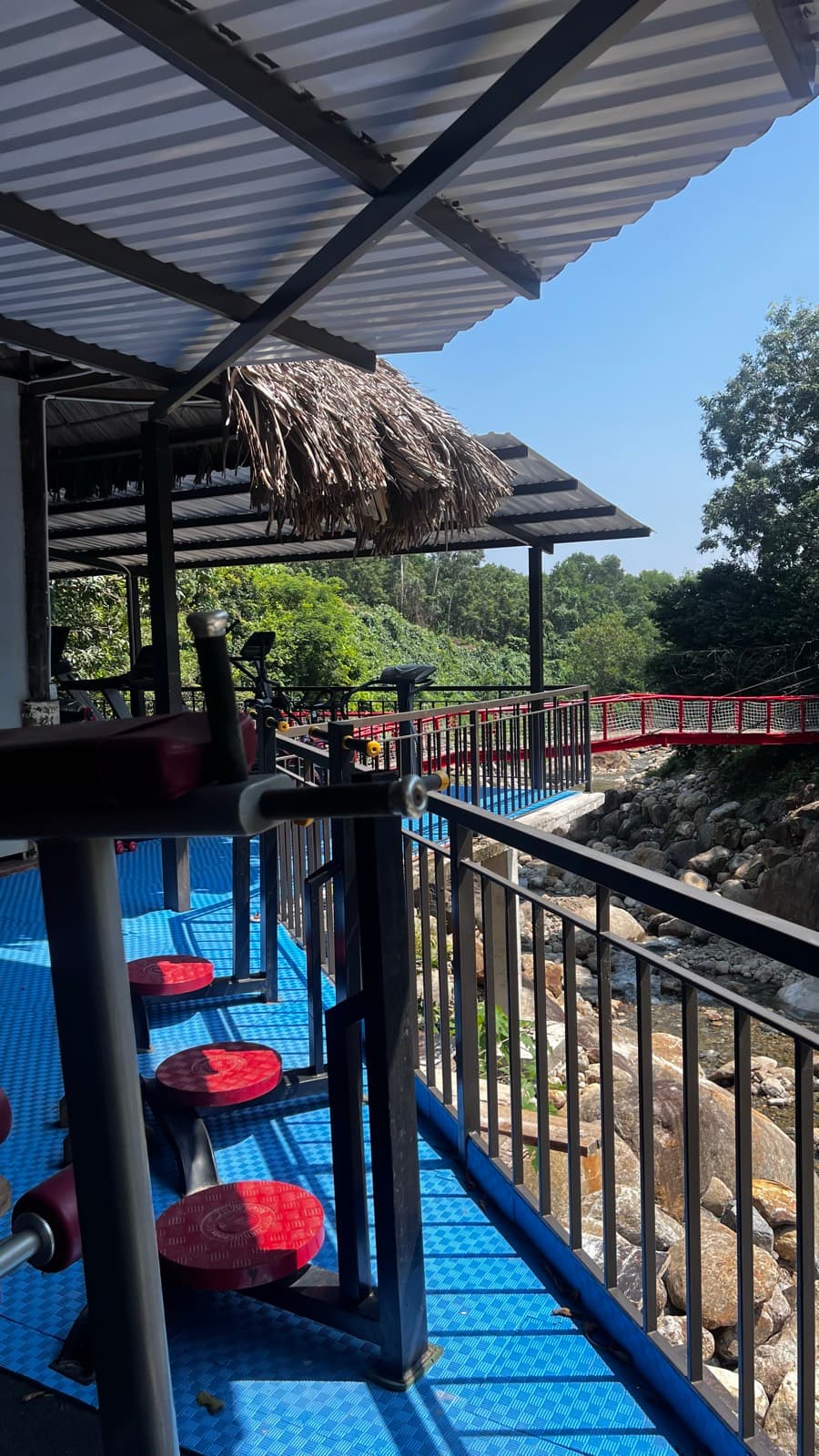 Suối Lương Hải Vân Park, exercise machines on a covered deck above the stream, with a red bridge