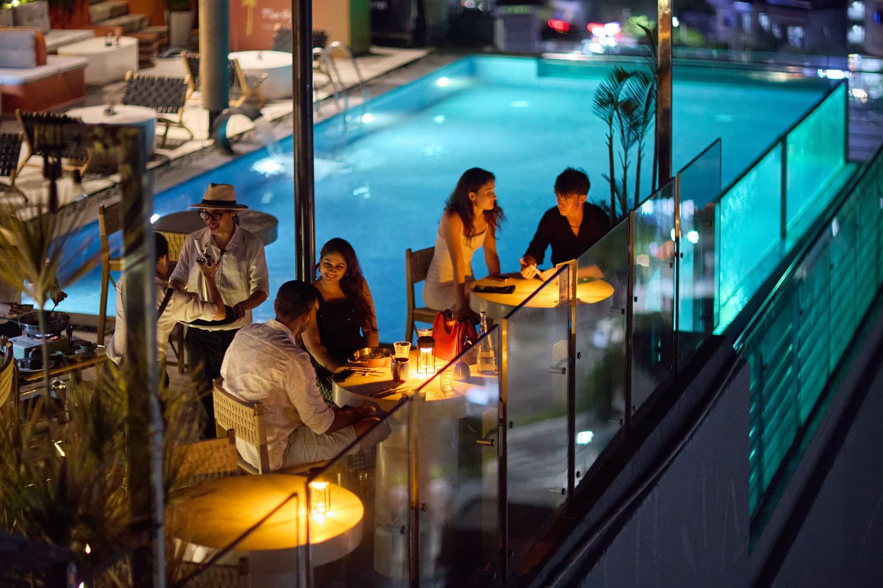 Tables by the lit pool on the roof of The Gypsy Rooftop Restaurant & Bar at night