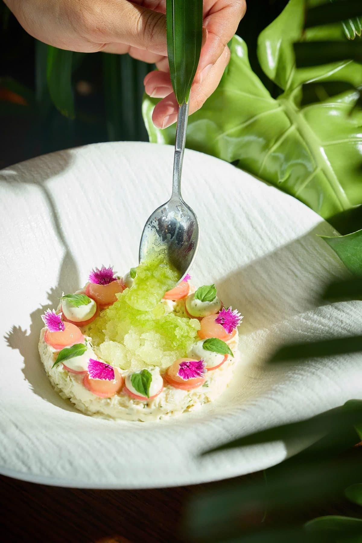 Local blue crab at The Gypsy Rooftop Restaurant & Bar, with green granita spooned over it and small pink flowers