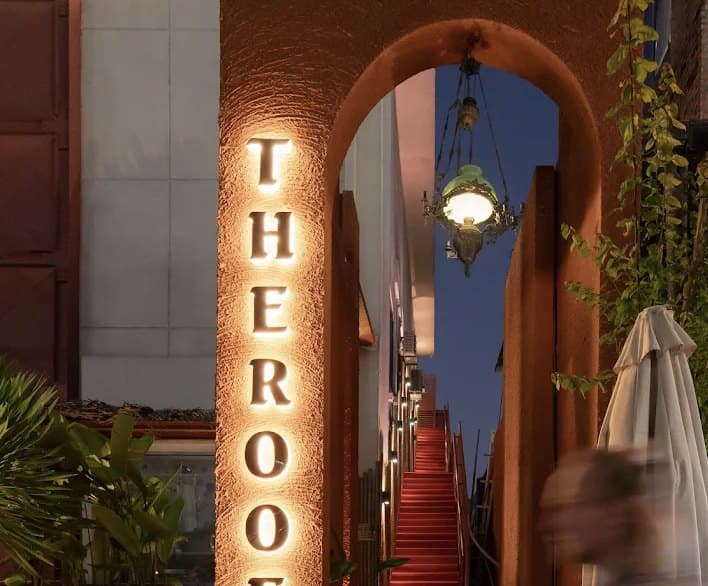 Lối vào The Roof: tên quán bằng chữ phát sáng trên vòm cửa, và cầu thang màu đỏ dẫn lên trên