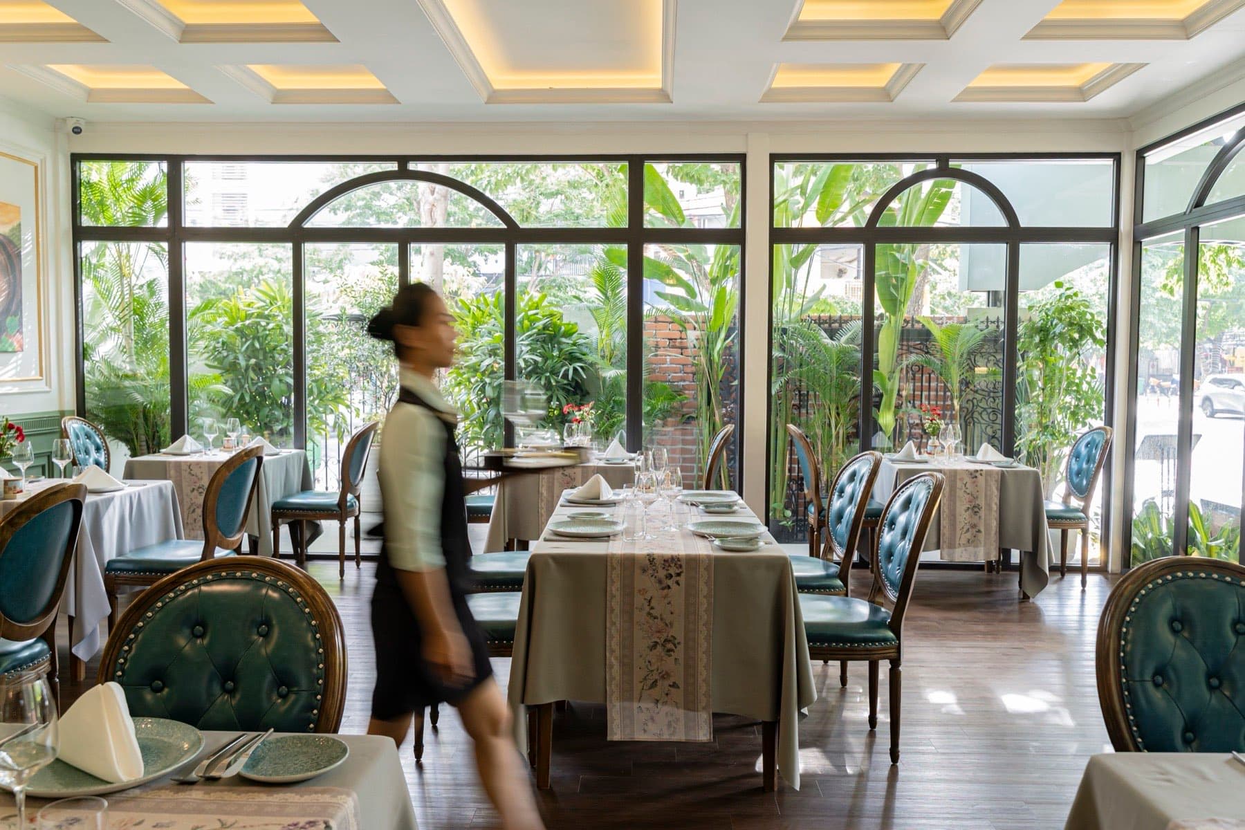 The Temptation, phòng ăn với cửa sổ vòm nhìn ra vườn và một nhân viên đang bưng khay