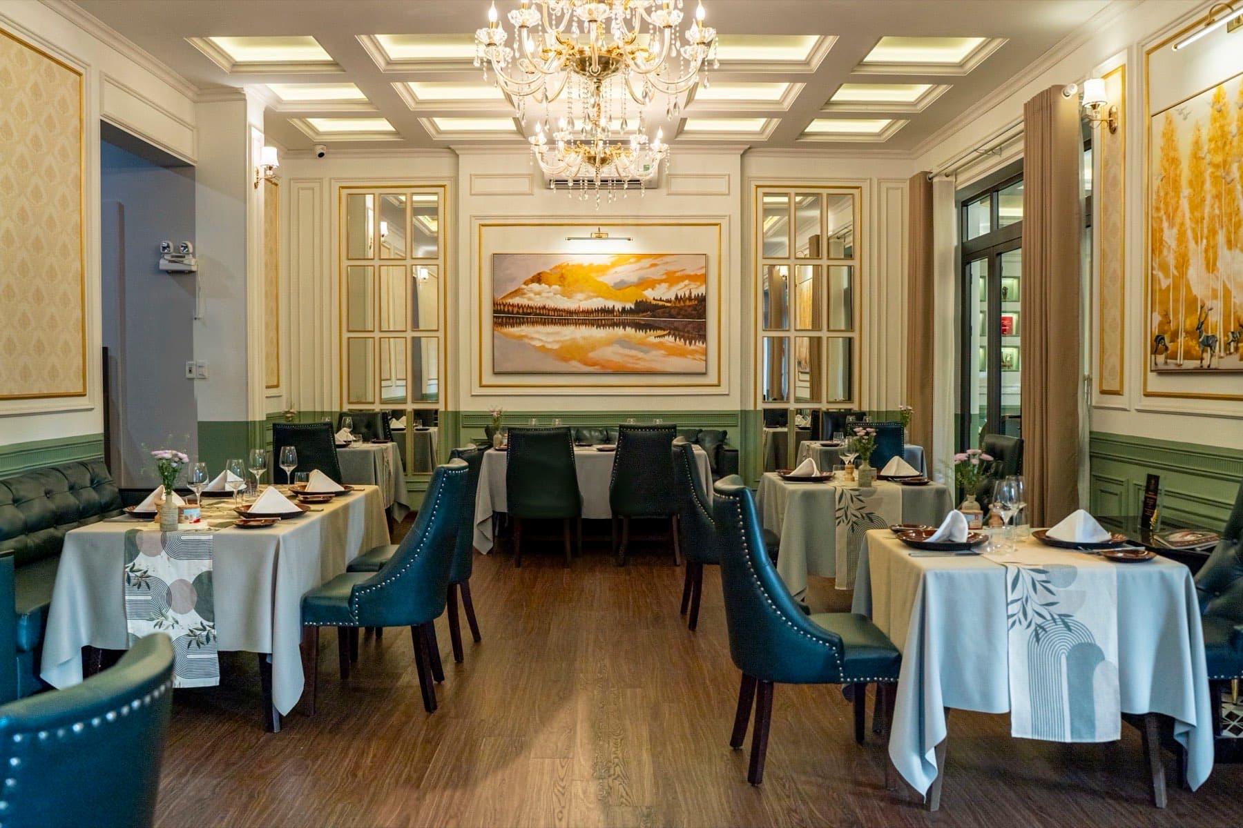 The Temptation, phòng ăn với đèn chùm, khăn bàn trắng và ghế da màu xanh