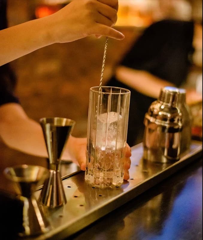 A bartender stirring a drink over ice at United Bar in Da Nang
