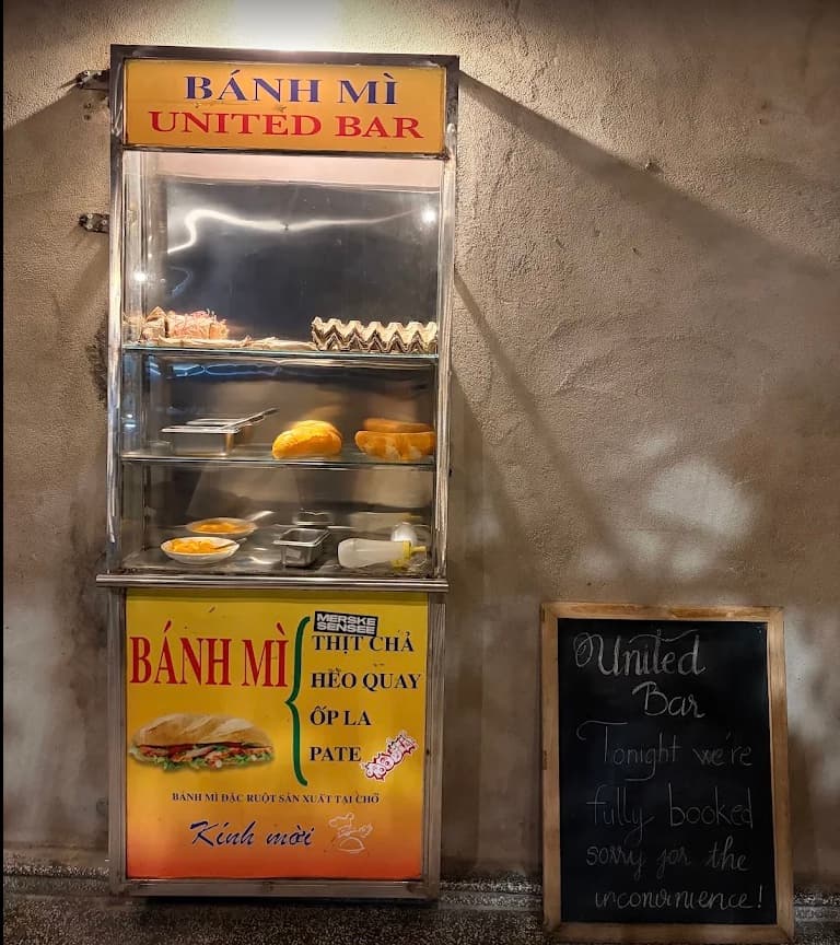 The banh mi cart that stands in front of United Bar in Da Nang, with a blackboard beside it saying the bar is fully booked tonight