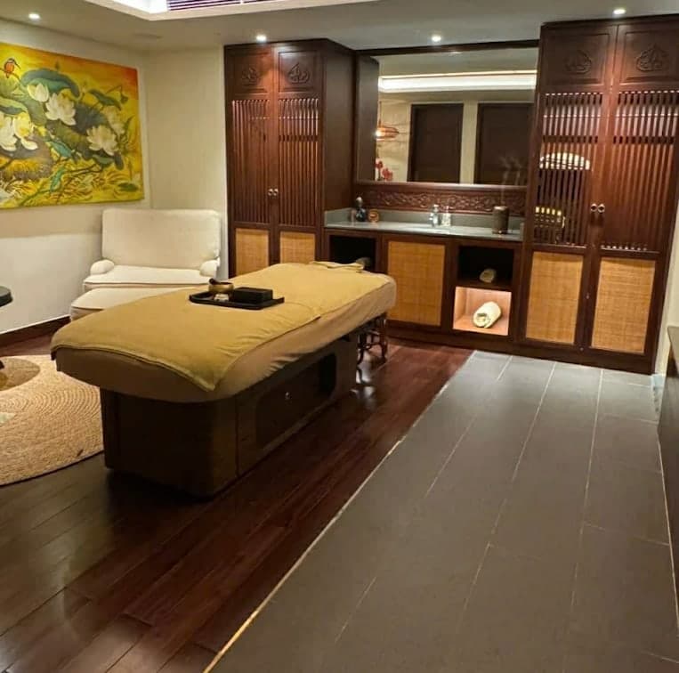 A treatment room at V-Senses Wellness & Spa with a bed, a tray and a cream armchair