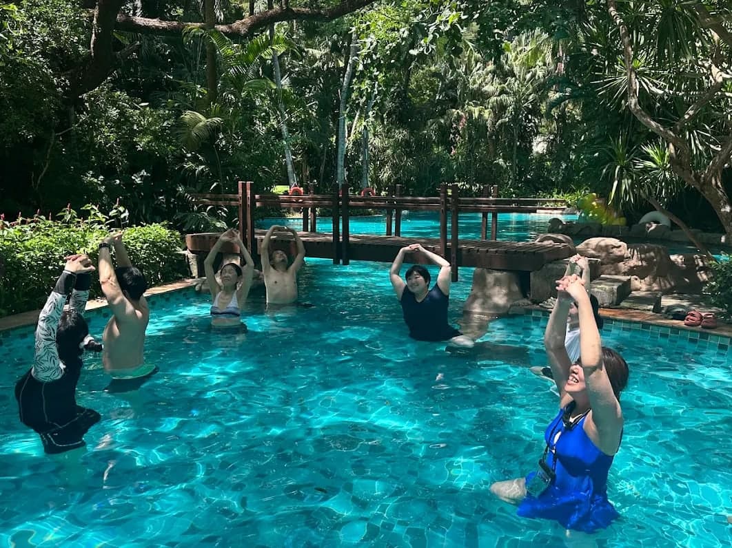A group in a garden pool raising their arms together