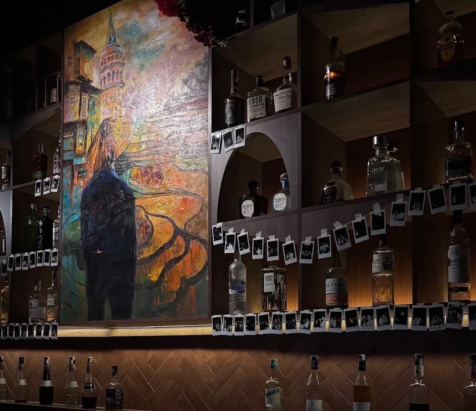 The back bar at Vấn Cocktail Bar in Da Nang, shelves of bottles strung end to end with polaroid photographs