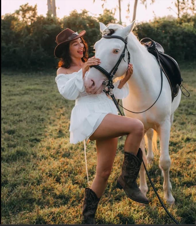 Vietnam Equestrian Club, a woman in a cowboy hat and a white dress with a white horse on grass at sunset
